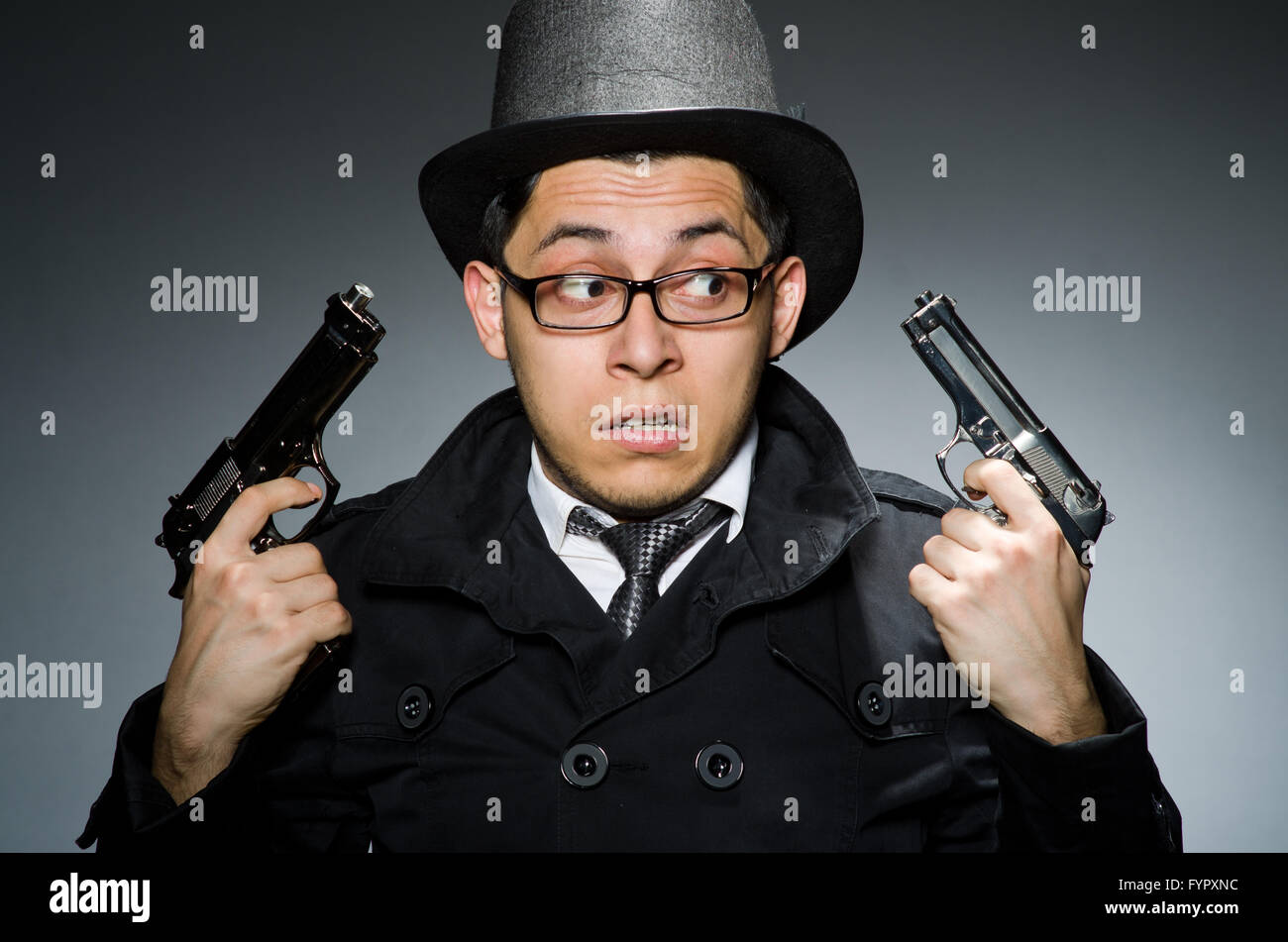 The criminal in black coat holding hadgun against gray Stock Photo