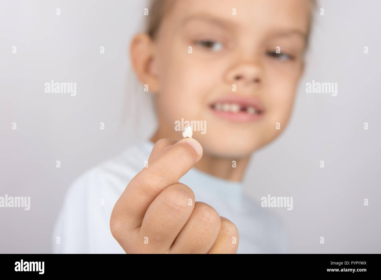 Six year old girl holding a fallen tooth and smiling looking at him Stock Photo