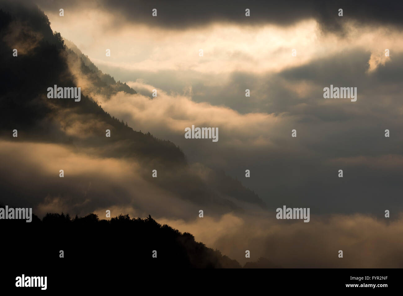 Fog on the mountainside above the Inn Valley, sun shining through clouds, Stans, Tyrol, Austria Stock Photo