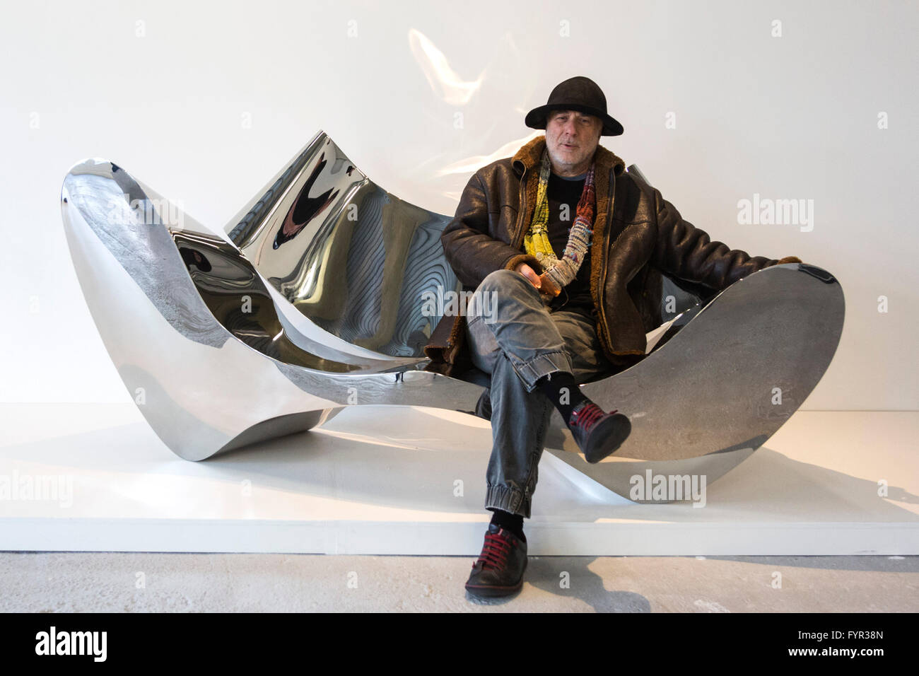 London, UK. 27 April 2016. Designer Ron Arad sits on the polished stainless  steel D-Sofa, 1994, which he designed. Donated for the auction by Johannes  and Helene Huth. Est. GBP 100,000-150,000. The