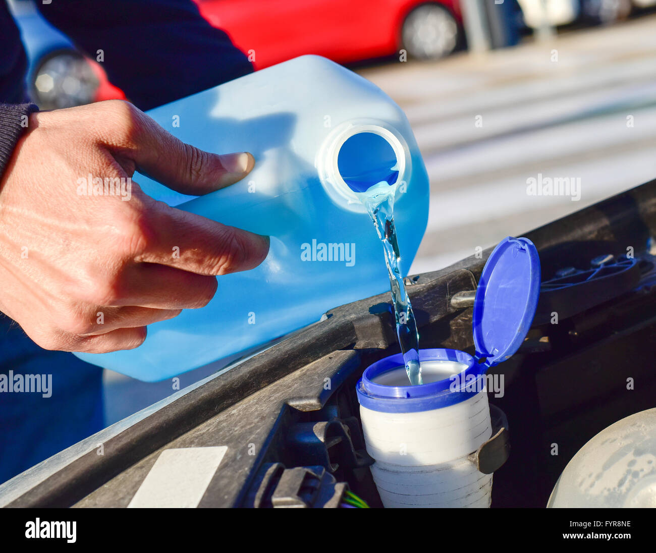 young man filling the tank of windshield washer fluid of a car Stock Photo