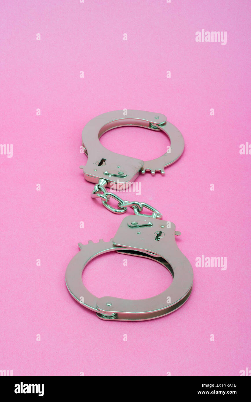 Silver metal handcuffs on pink background Stock Photo