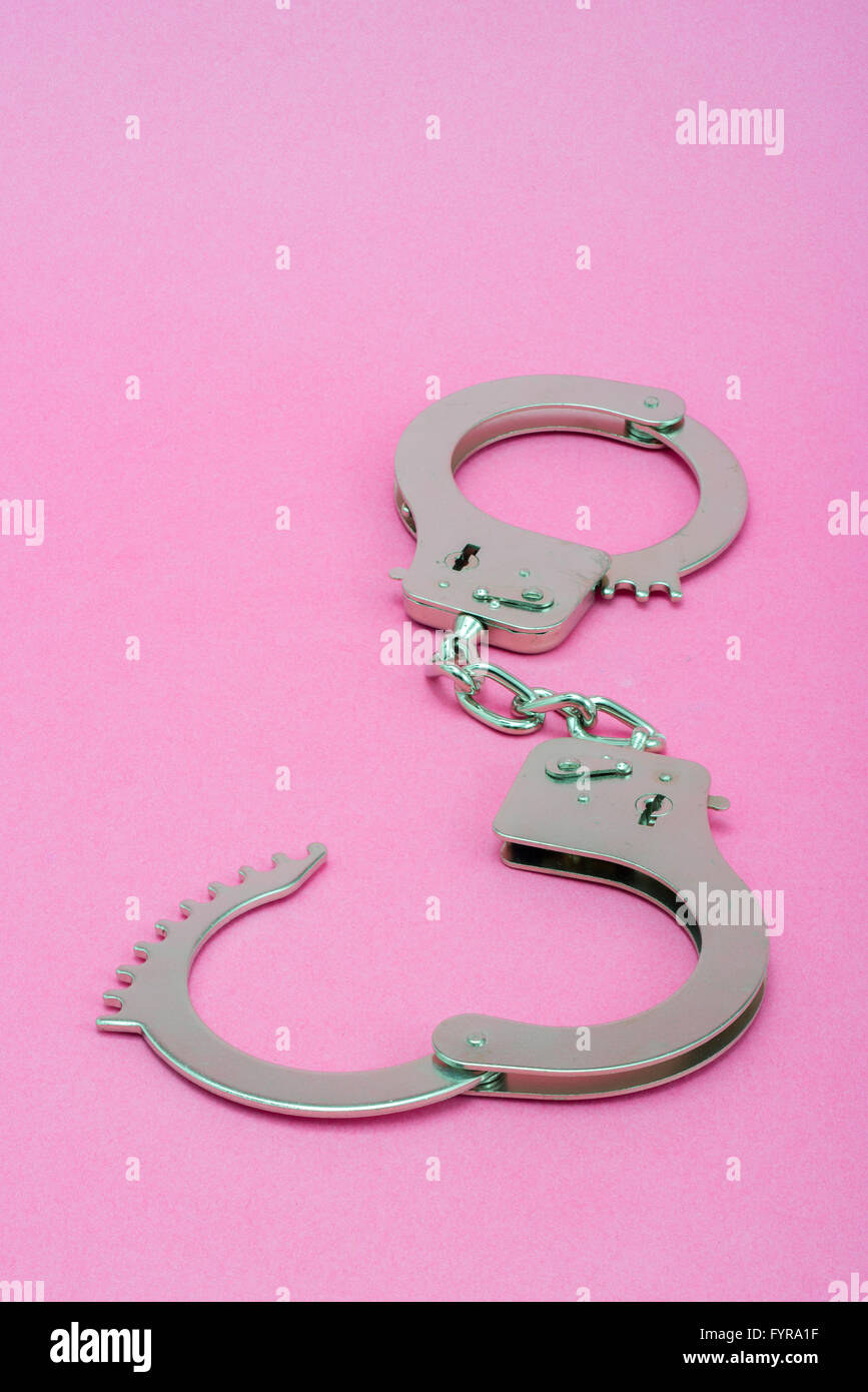 Silver metal handcuffs on pink background Stock Photo
