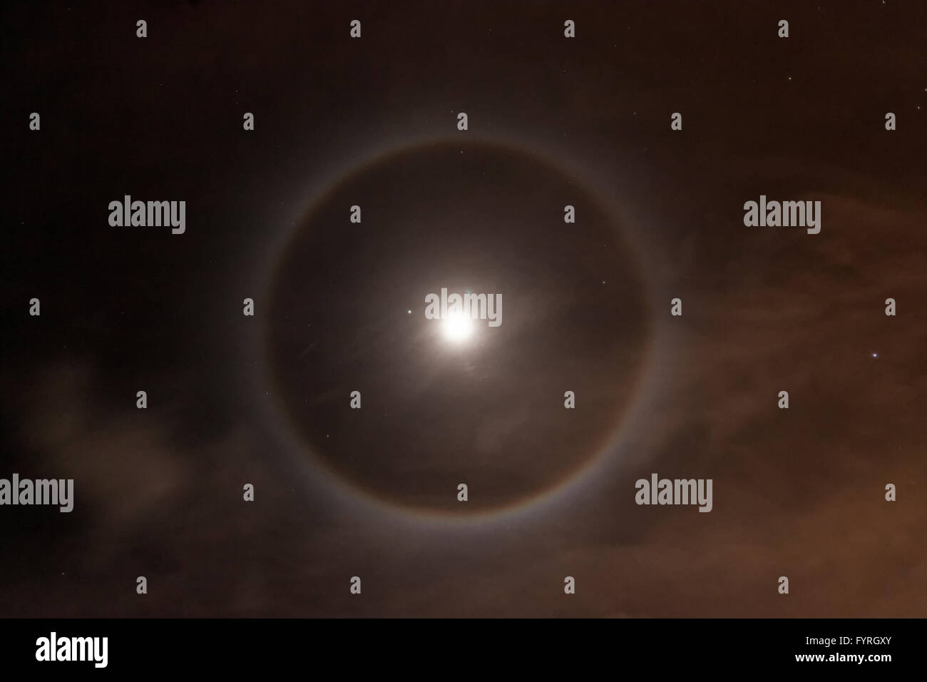 '22 Degree Halo' Ice crystals refracting light forming a circle around the moon (or sun). Stock Photo