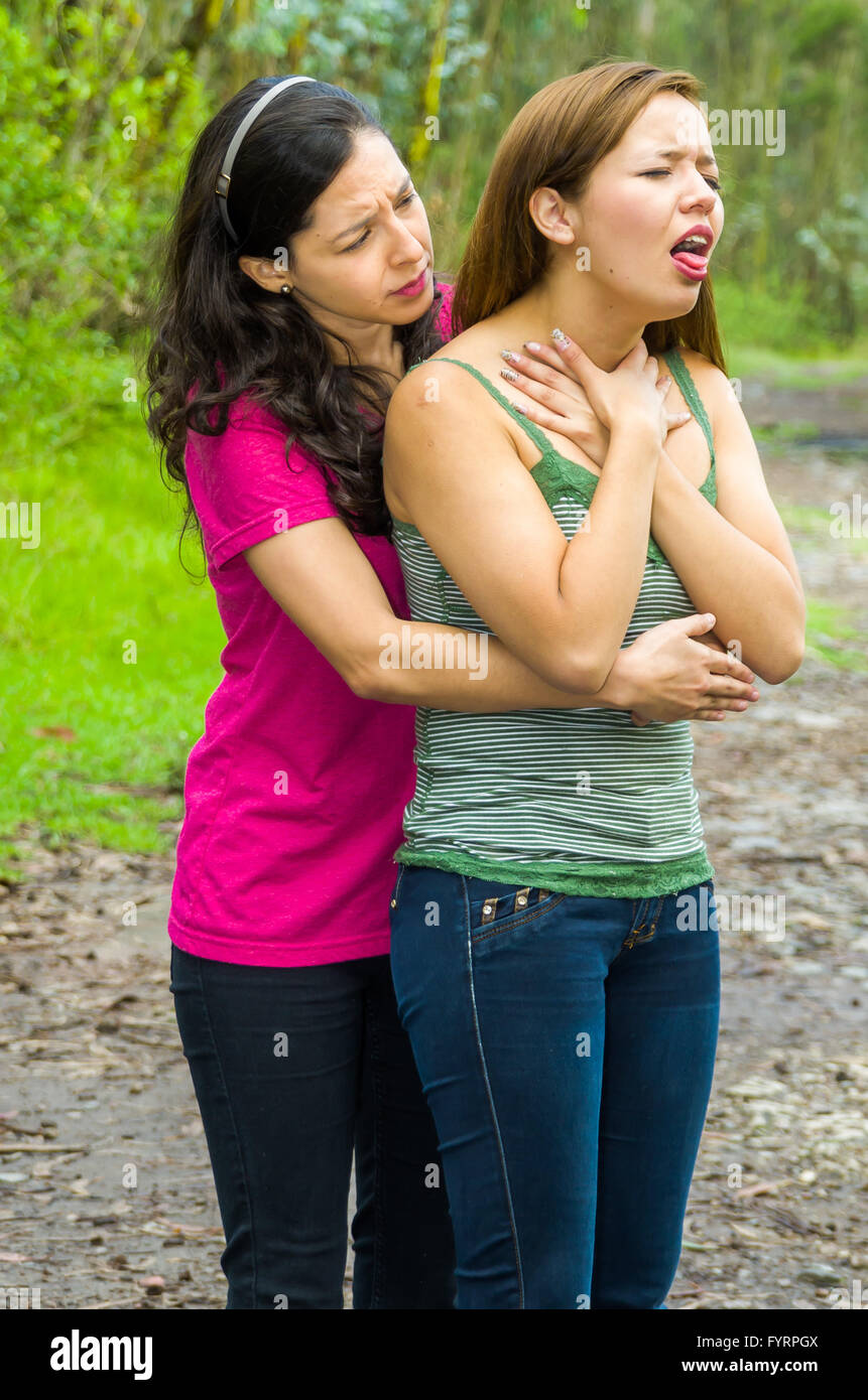 Young Woman Choking With Lady Standing Behind Performing Heimlich Maneuver Park Environment And 