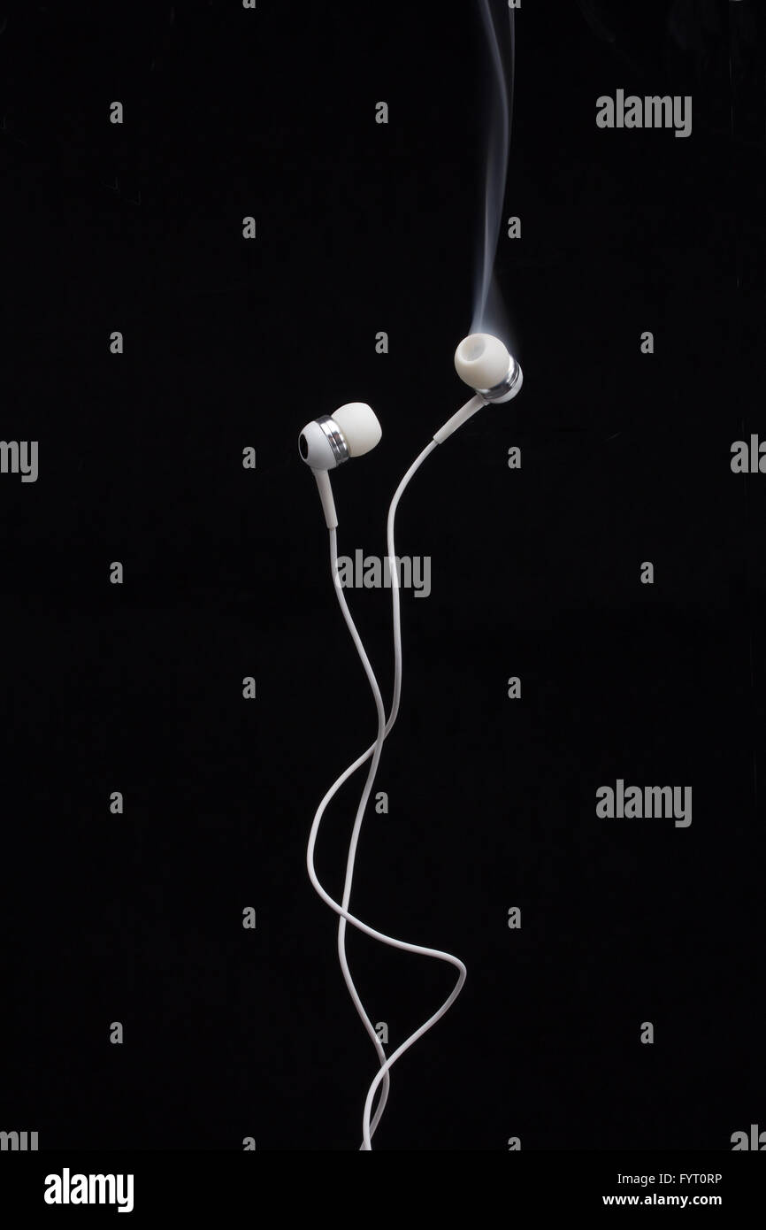 Headphones smoking after a hard music session on a black background Stock Photo