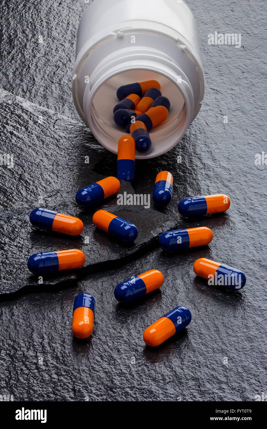 white canister and capsules on black slate background Stock Photo