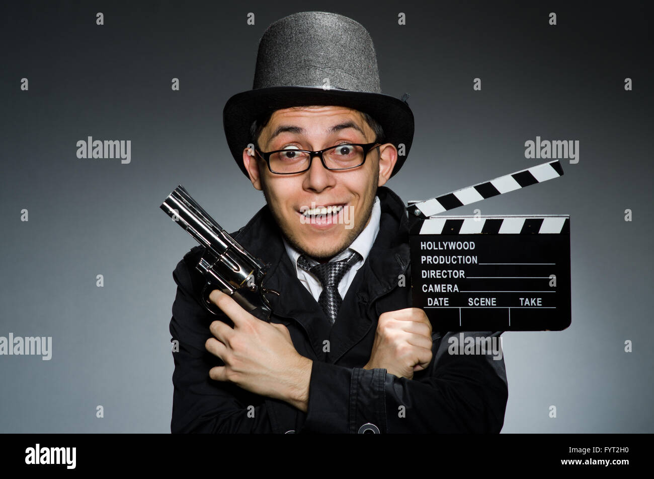 The young man with weapon and clapboard against gray Stock Photo