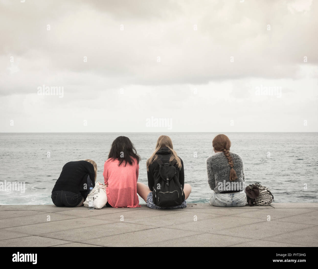 Four teenage girls looking out to sea. Stock Photo