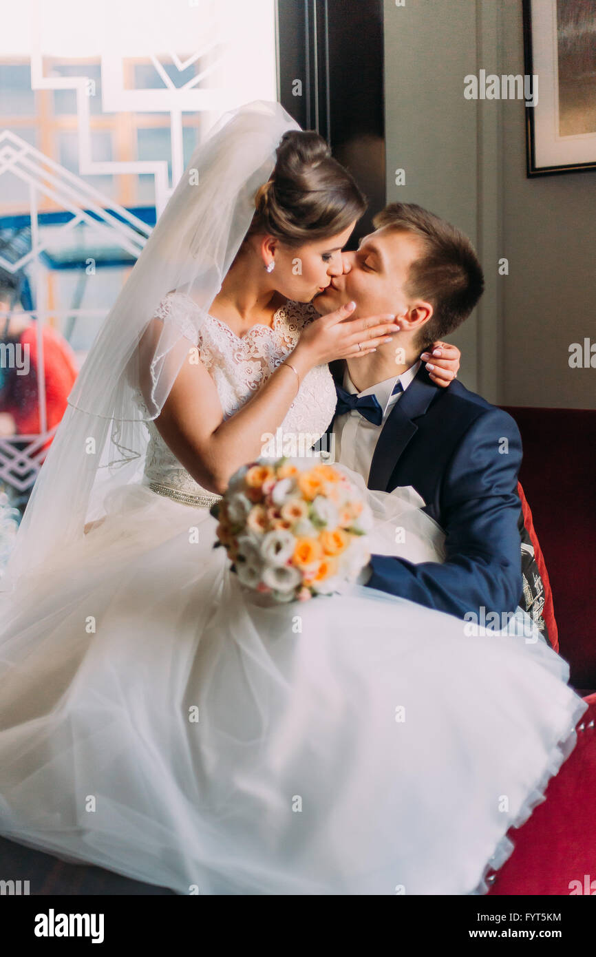 Close-up photo of bride and groom sitting in a luxurious chair on his ...