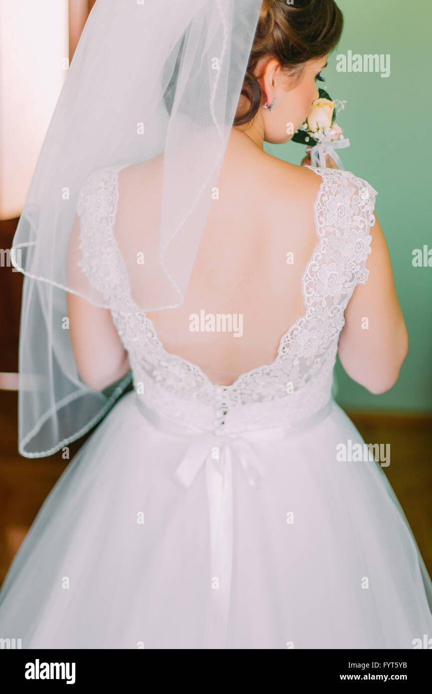 Beautiful bride in lace wedding dress standing with his back to the ...