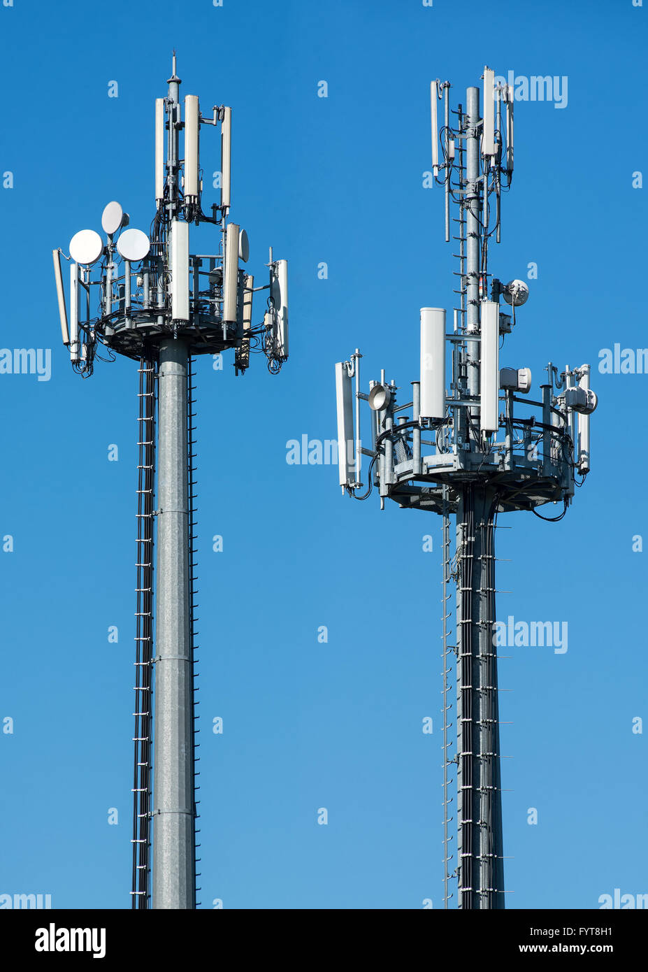 Two telecommunications towers with satellite dishes and antennae fro transmitting and receiving broadcasting signals Stock Photo