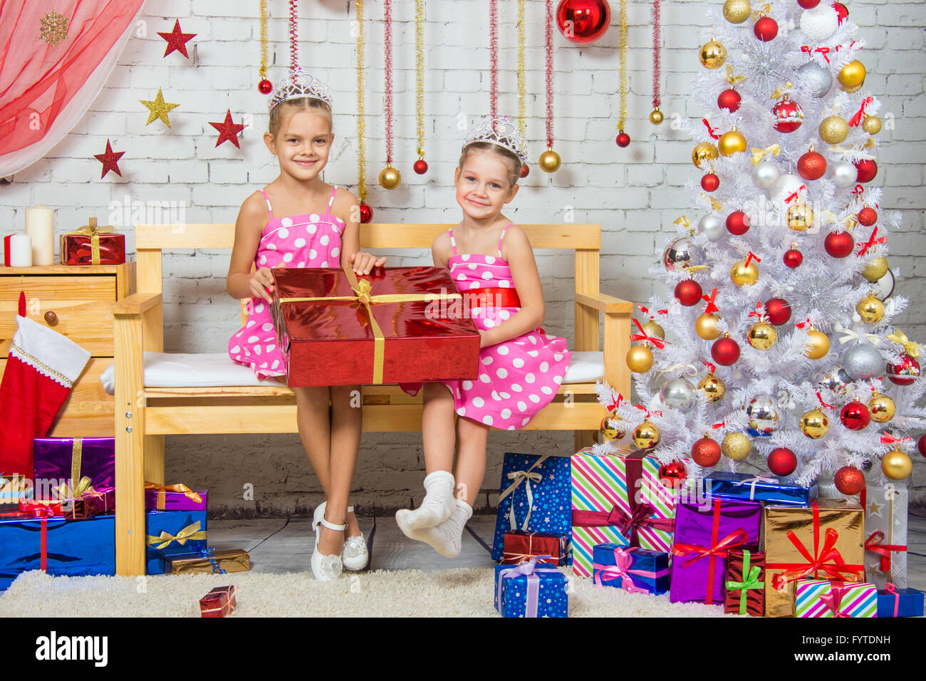 Happy girl who gave a great gift sitting on a bench in a Christmas setting Stock Photo