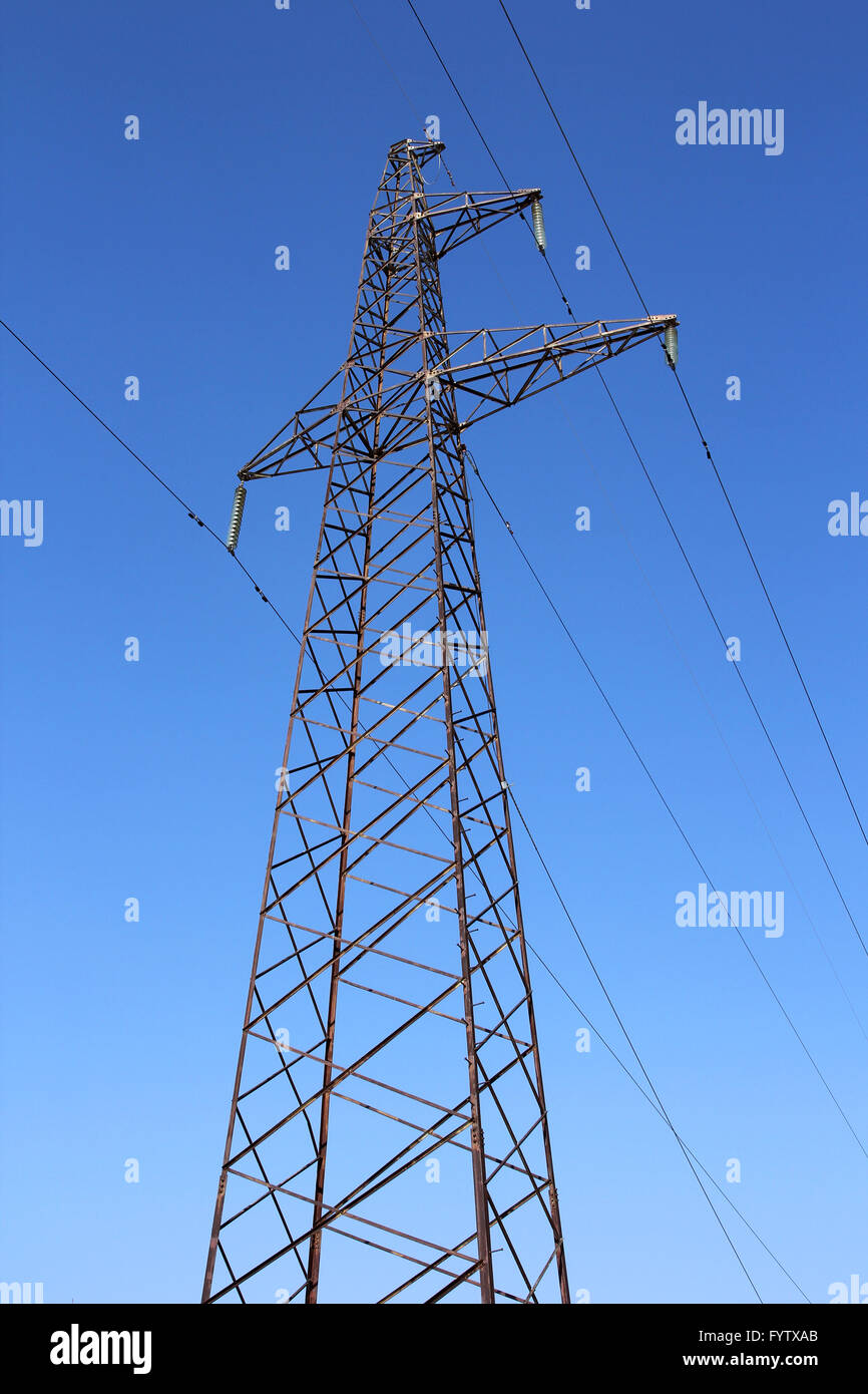 High voltage power pylons against blue sky Stock Photo