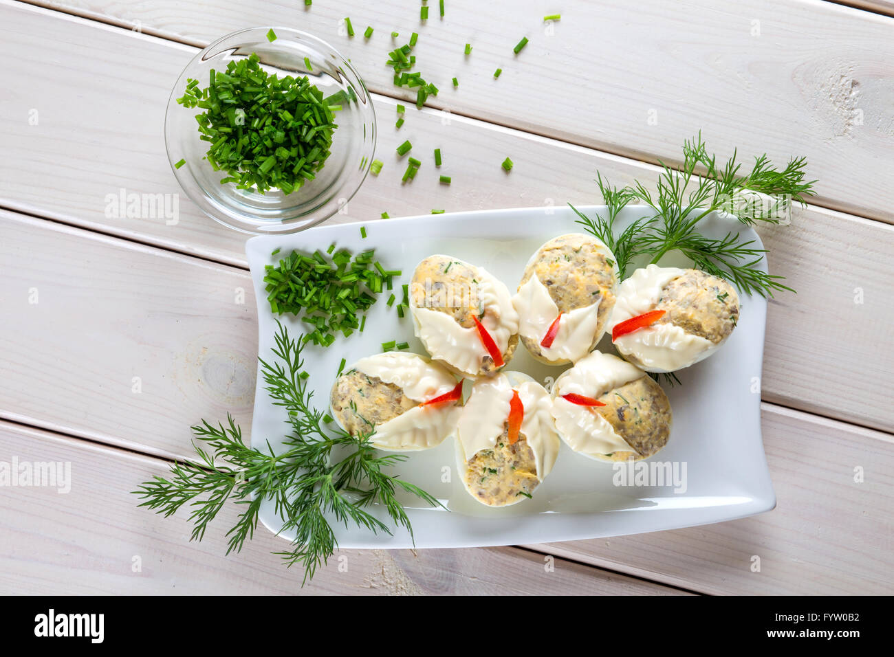 Dish with hard boiled eggs in mayonnaise parsley nad chopped chives, on white plank background Stock Photo