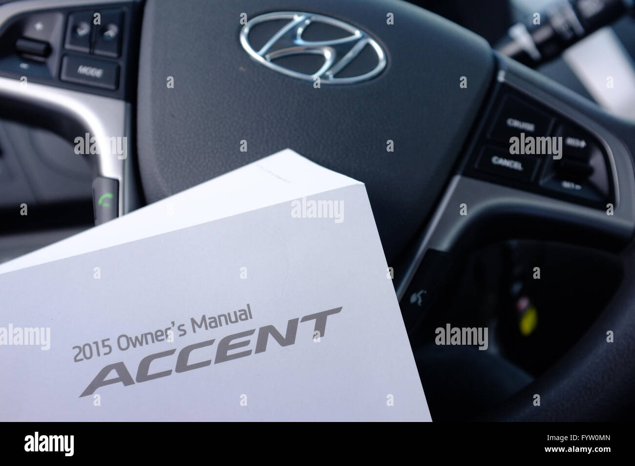 A Hyundai Accent Owner's Manual in front of a Hyundai steering wheel. - Stock Image