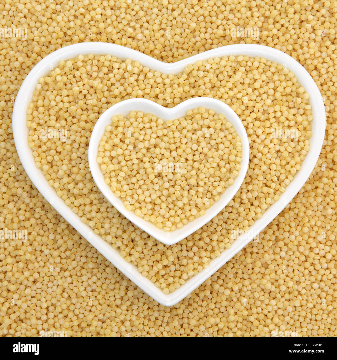 Pearl couscous in heart shaped bowls forming an abstract background. Stock Photo