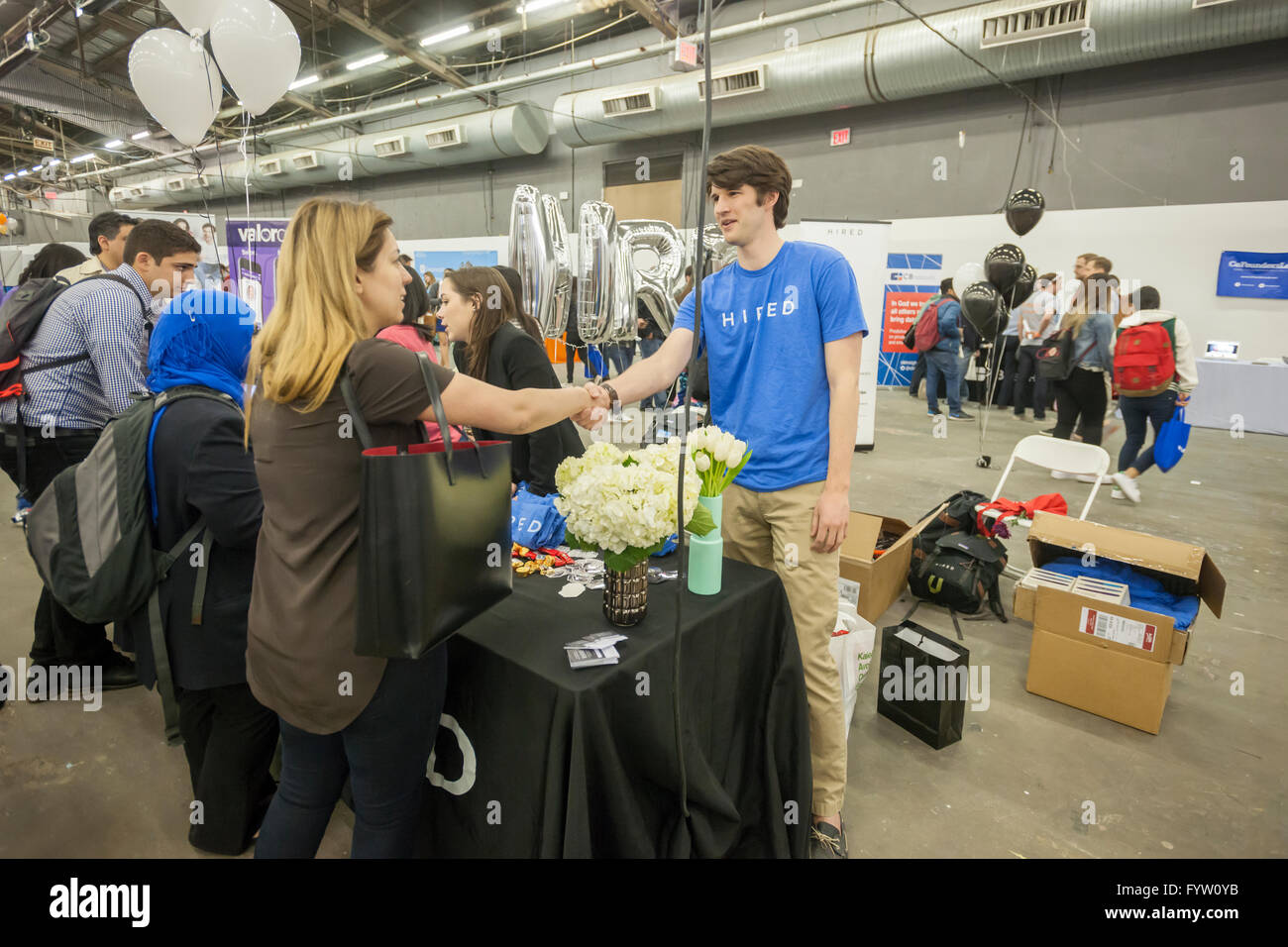 Worker from Hired greets a job seeker at the TechDay New York event on Thursday, April 21, 2016. Thousands attended to seek jobs with the startups and to network with their peers. TechDay bills itself as the world's largest startup event with over 300 exhibitors. (© Richard B. Levine) Stock Photo