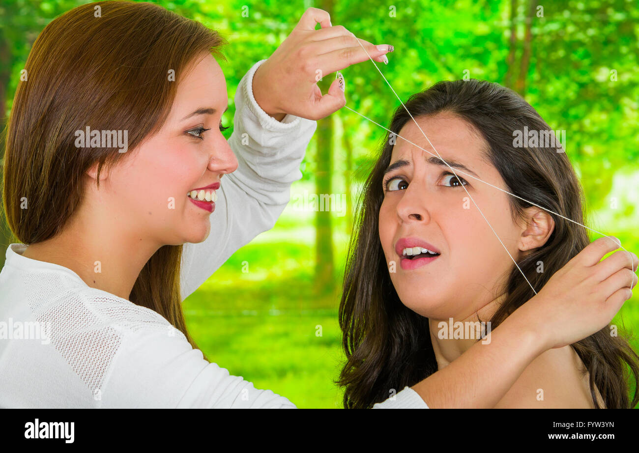 Woman receiving eyebrow hair removal, scared look on face, threading