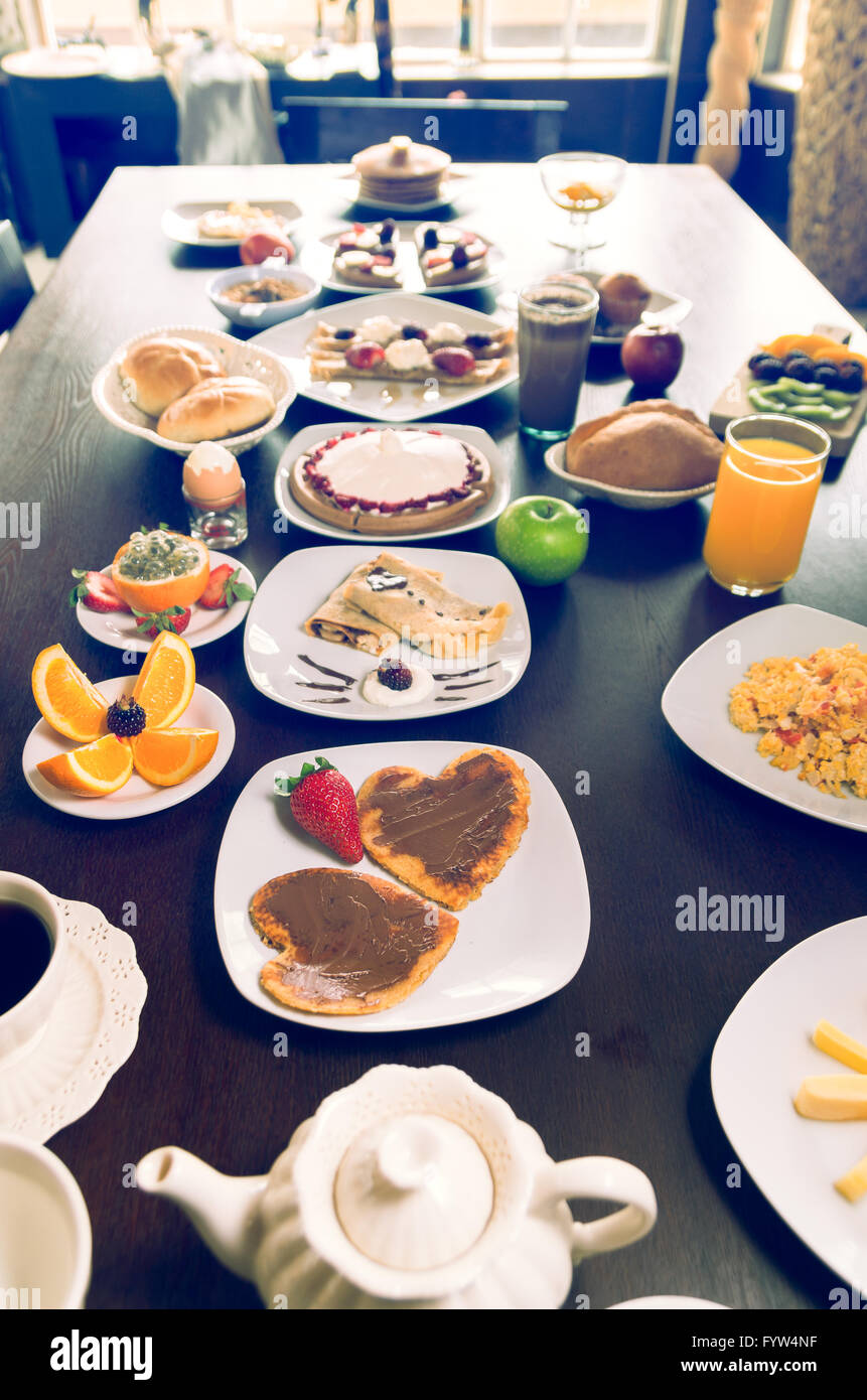 Breakfast buffet shot from one end of table showing selection with crepes, waffles, juices, eggs, coffee and fruits Stock Photo