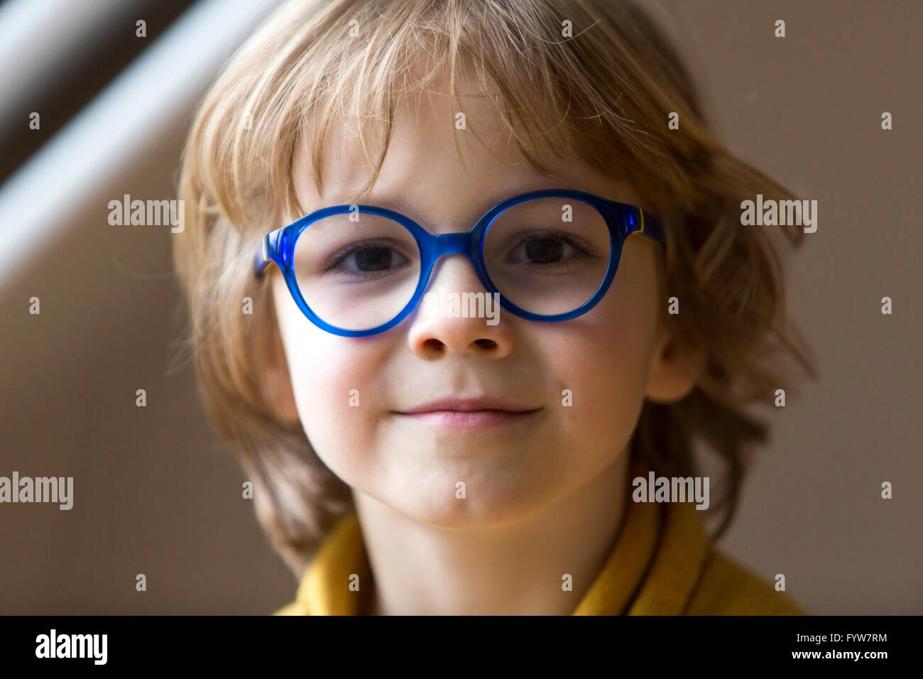 Young boy, 6 years old, looks friendly, smiles, with glasses, with a blue frame, Stock Photo
