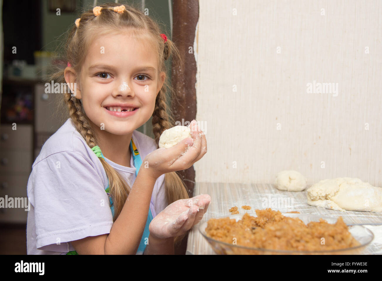 Cheerful girl stained with flour made patty with cabbage Stock Photo
