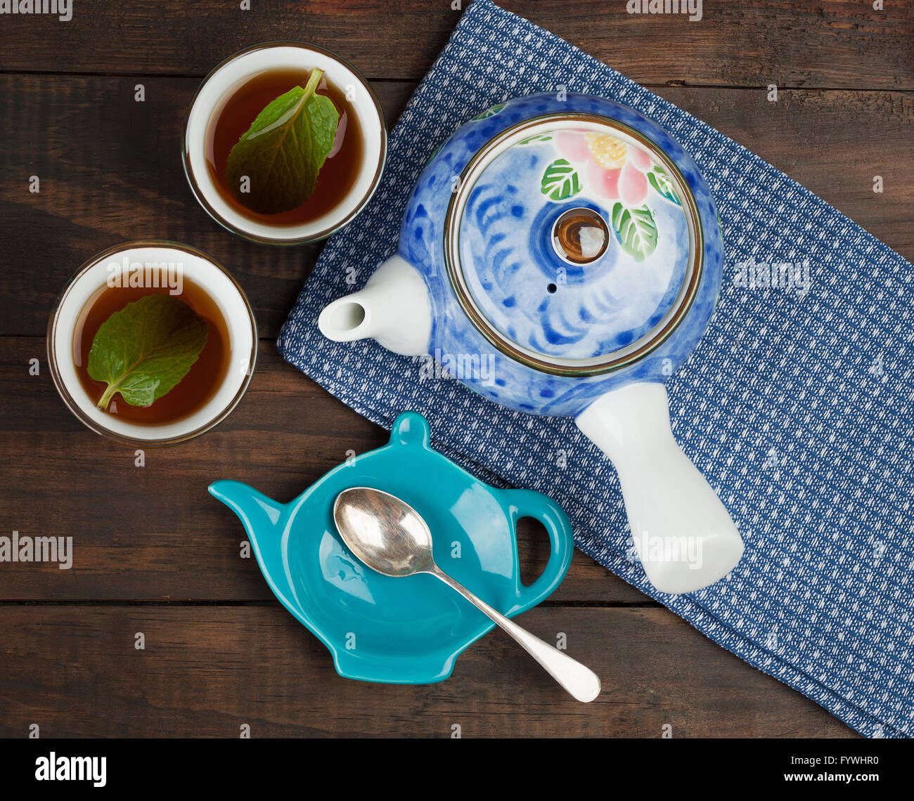 Two cups of black tea, teapot on towel and spoon. Top view with copy space Stock Photo