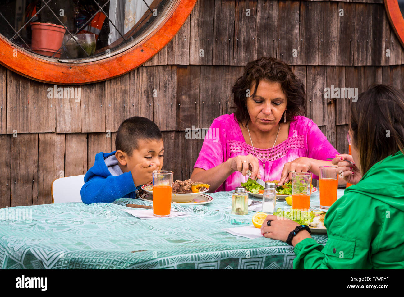 Two children having lunch with their mother at a restaurant in Dalcahue, Chile, South America. Stock Photo