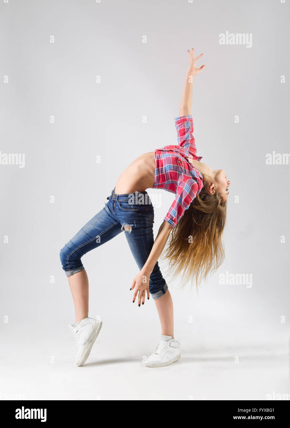 Young modern dancing girl in jeans on grey Stock Photo