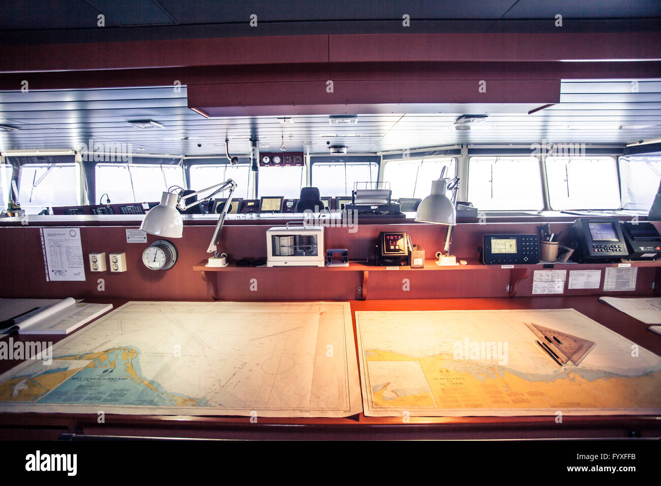 Maps laying on a table on the navigation deck of a container ship. Stock Photo