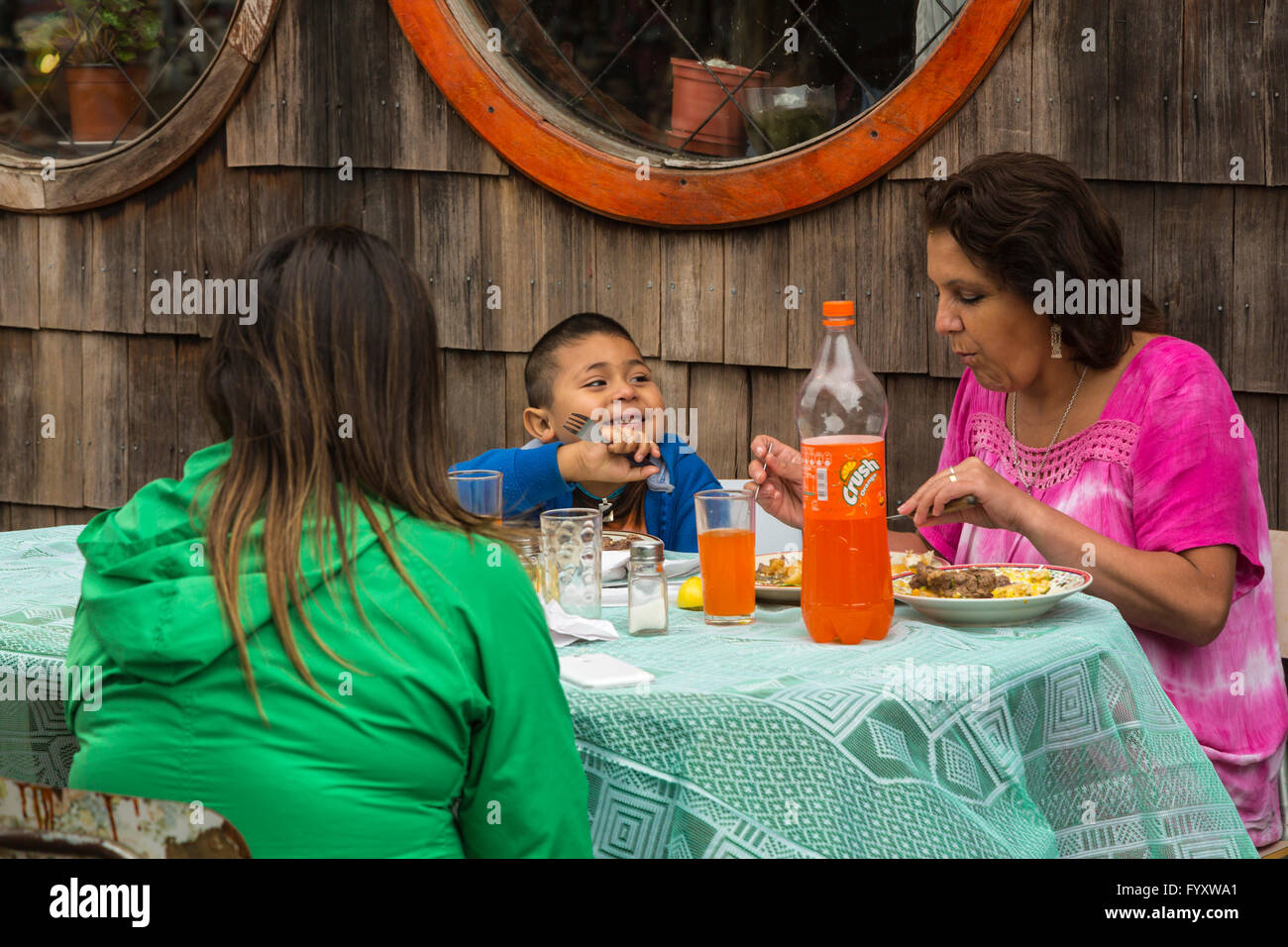 Two children having lunch with their mother at a restaurant in Dalcahue, Chile, South America. Stock Photo