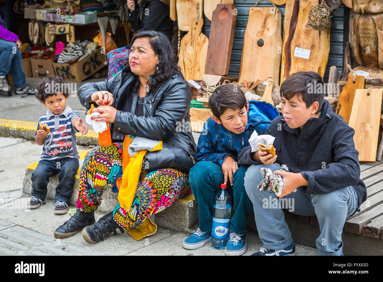 A mother and three boys having and empanada lunch on the sidewalk in Dalcahue, Chile, South America. Stock Photo