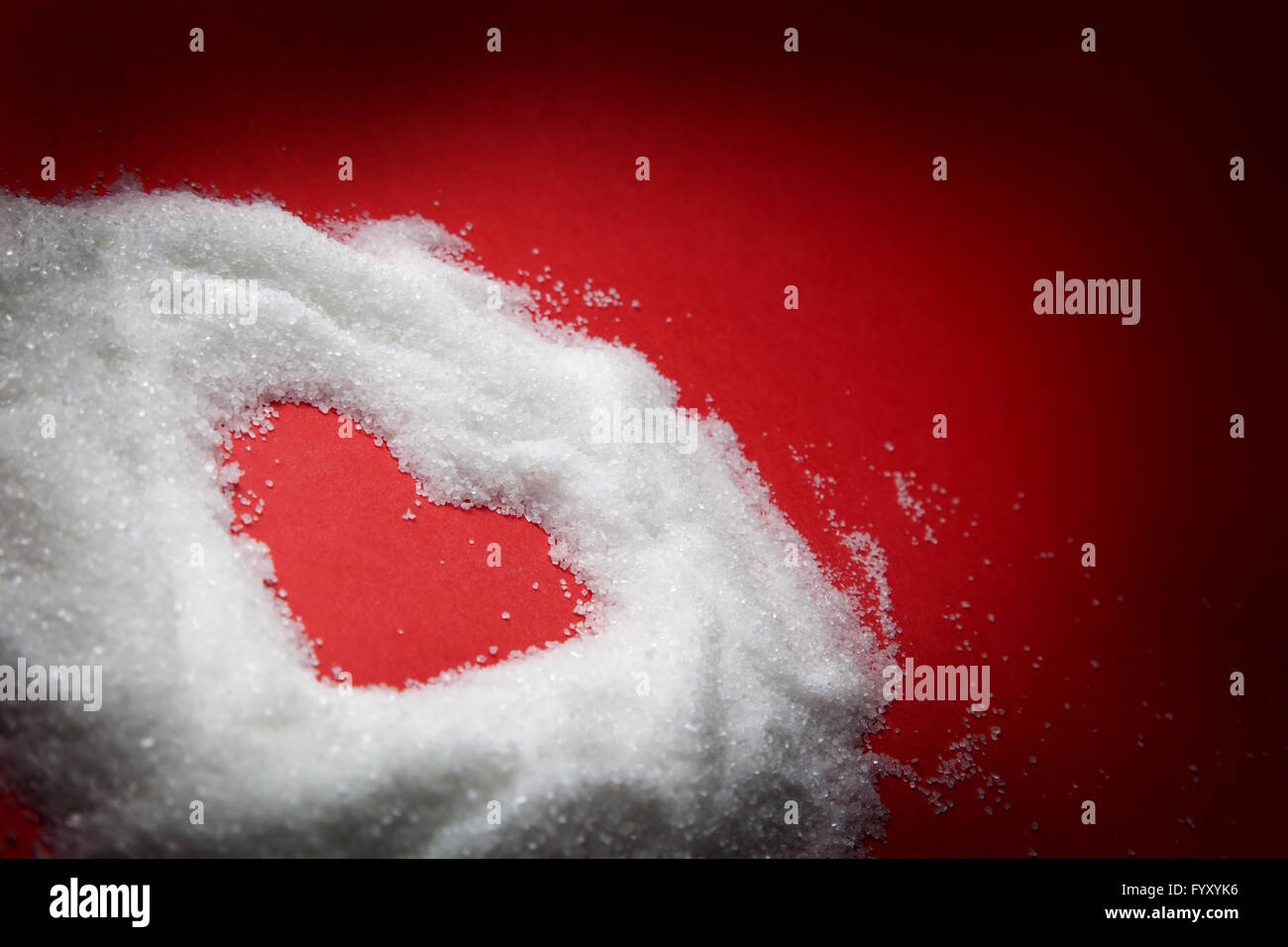 Heart shape in sugar on red background Stock Photo - Alamy
