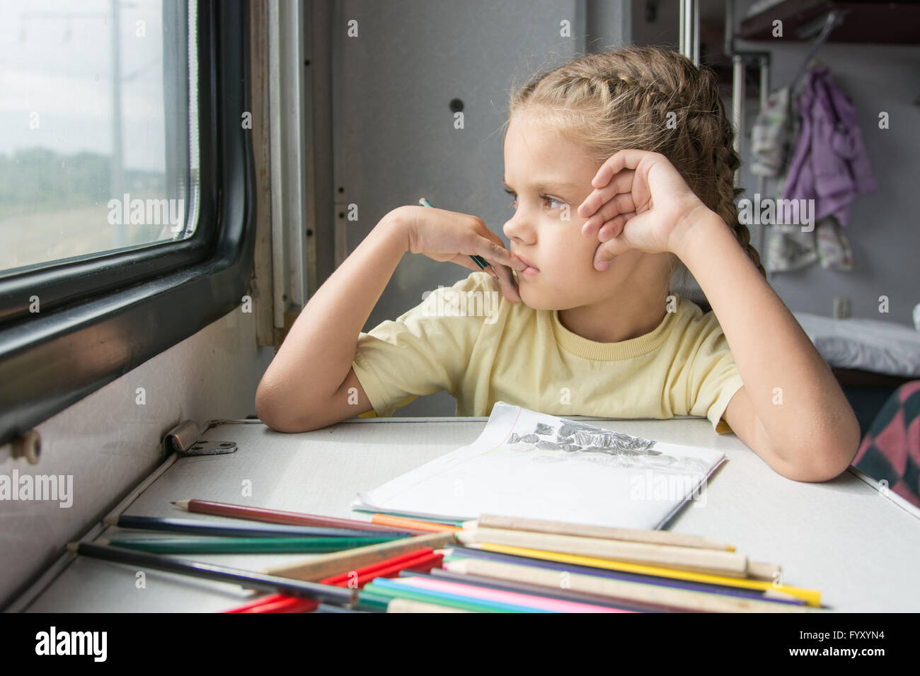 The girl looked out the window thinking drawing pencils in a train ...