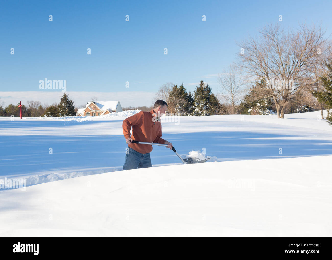Senior adult man trying to dig out drive in snow Stock Photo