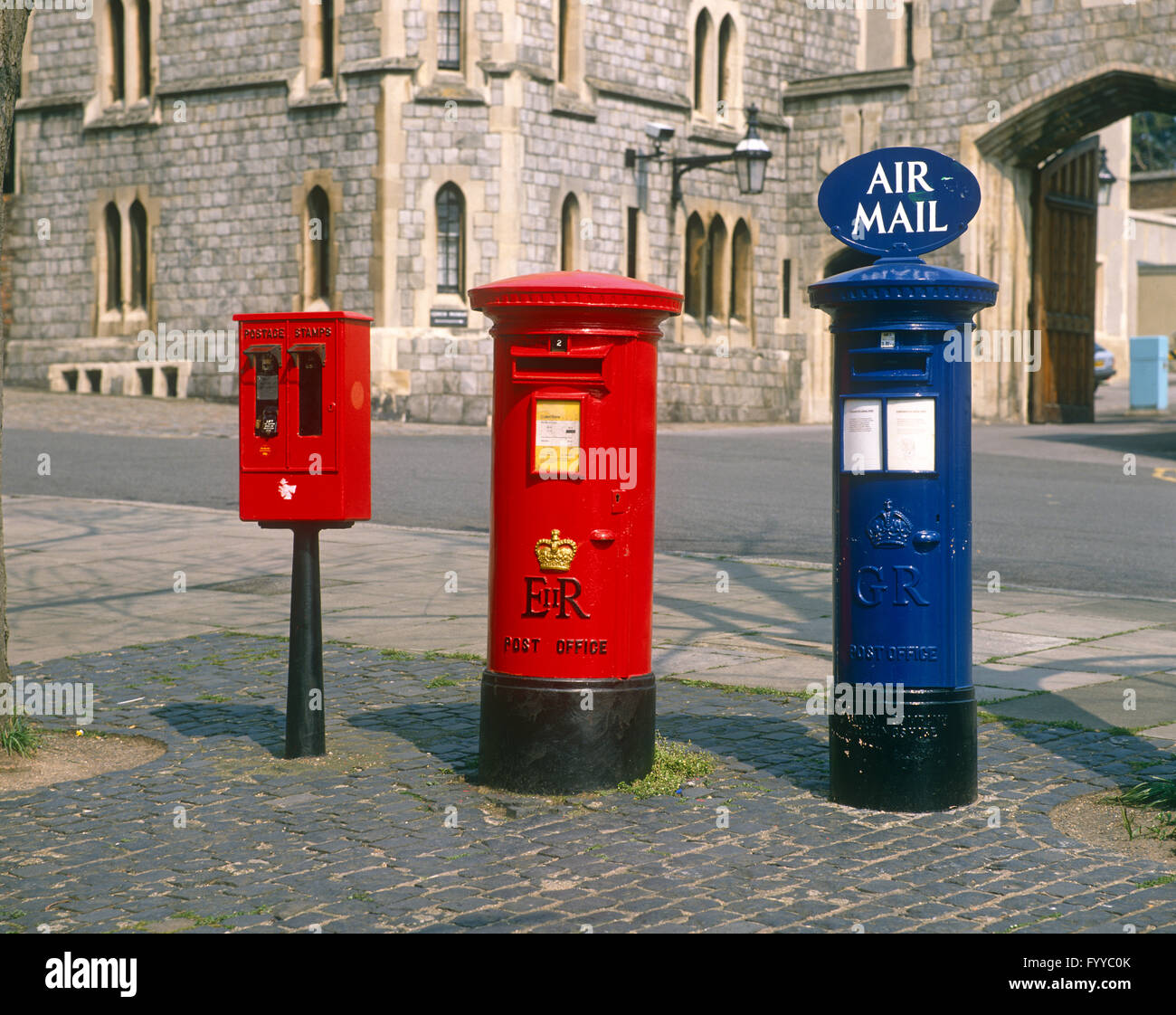 A set of three differently coloured postboxes, outside. Stock Photo