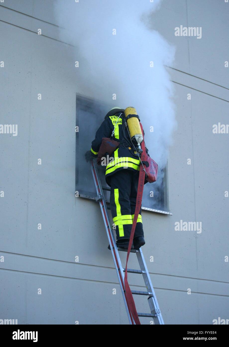 Emergency services exercise of the Frankfurt fire brigade on april-09-2016. A fireman with breathing protection equipment try to enter a smoky building. Stock Photo
