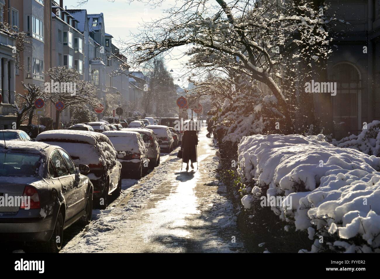 An old woman with walking aids on the snowy and icily pavement in ...