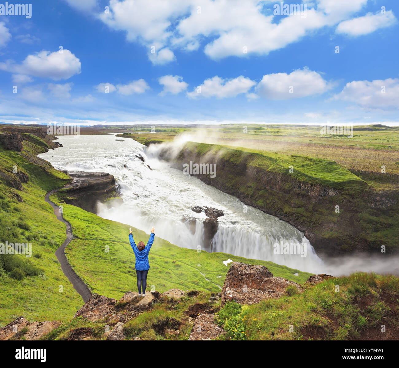 Delighted woman tourist on the shore of the waterfall. Gyullfoss, Iceland Stock Photo