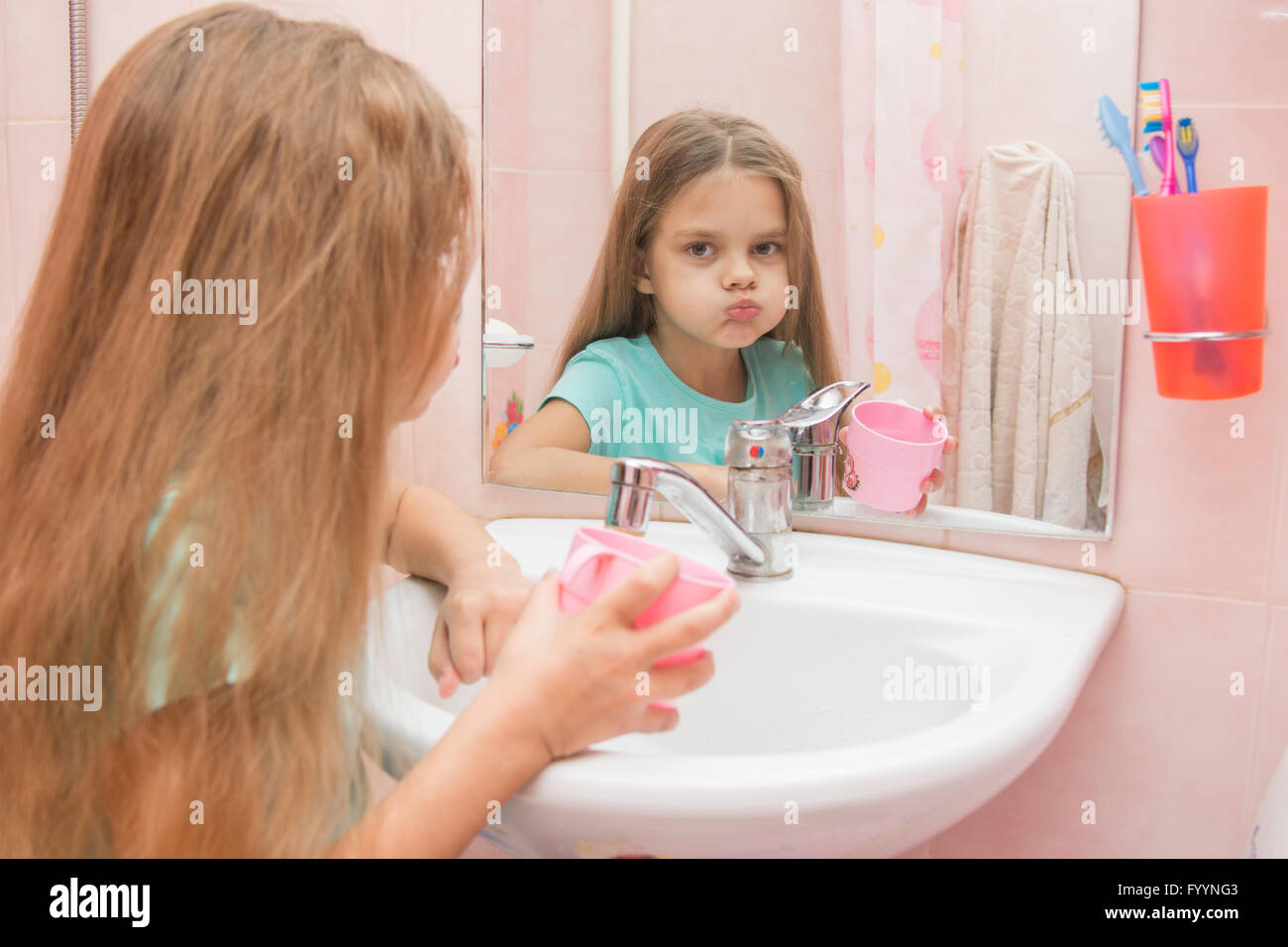 Girl rinse your mouth in the bathroom and look in the frame Stock Photo