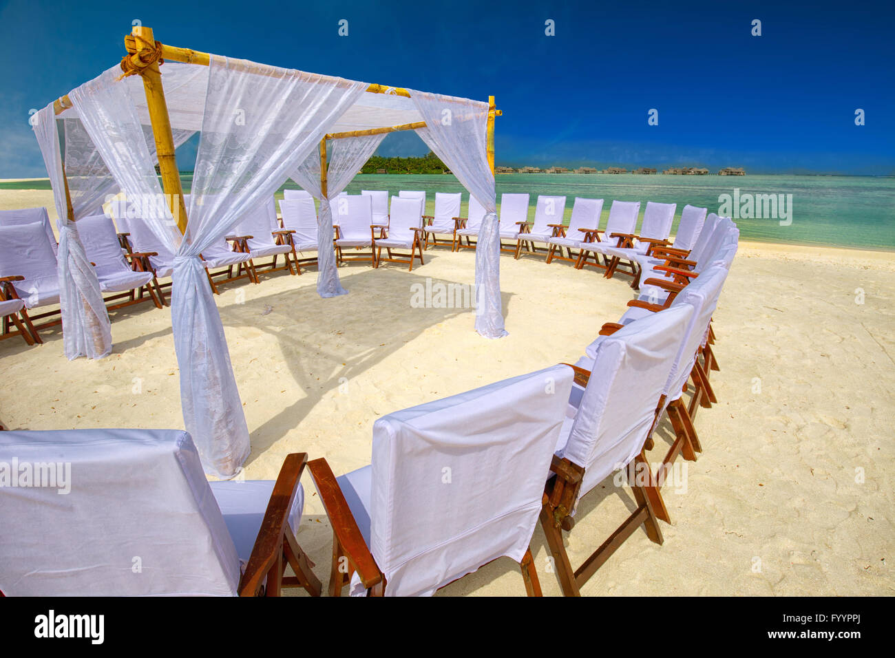 Decorated chairs and arch for wedding ceremony on tropical island with sandy beach and tourquise clear water Stock Photo
