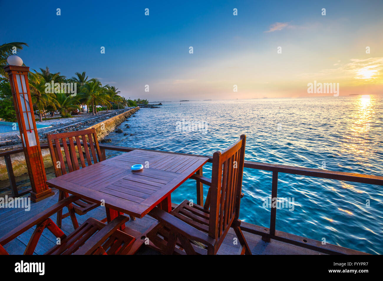Beautiful sunset from restaurant on the beach. Tropical island with sandy beach, palm trees and tourquise clear water Stock Photo