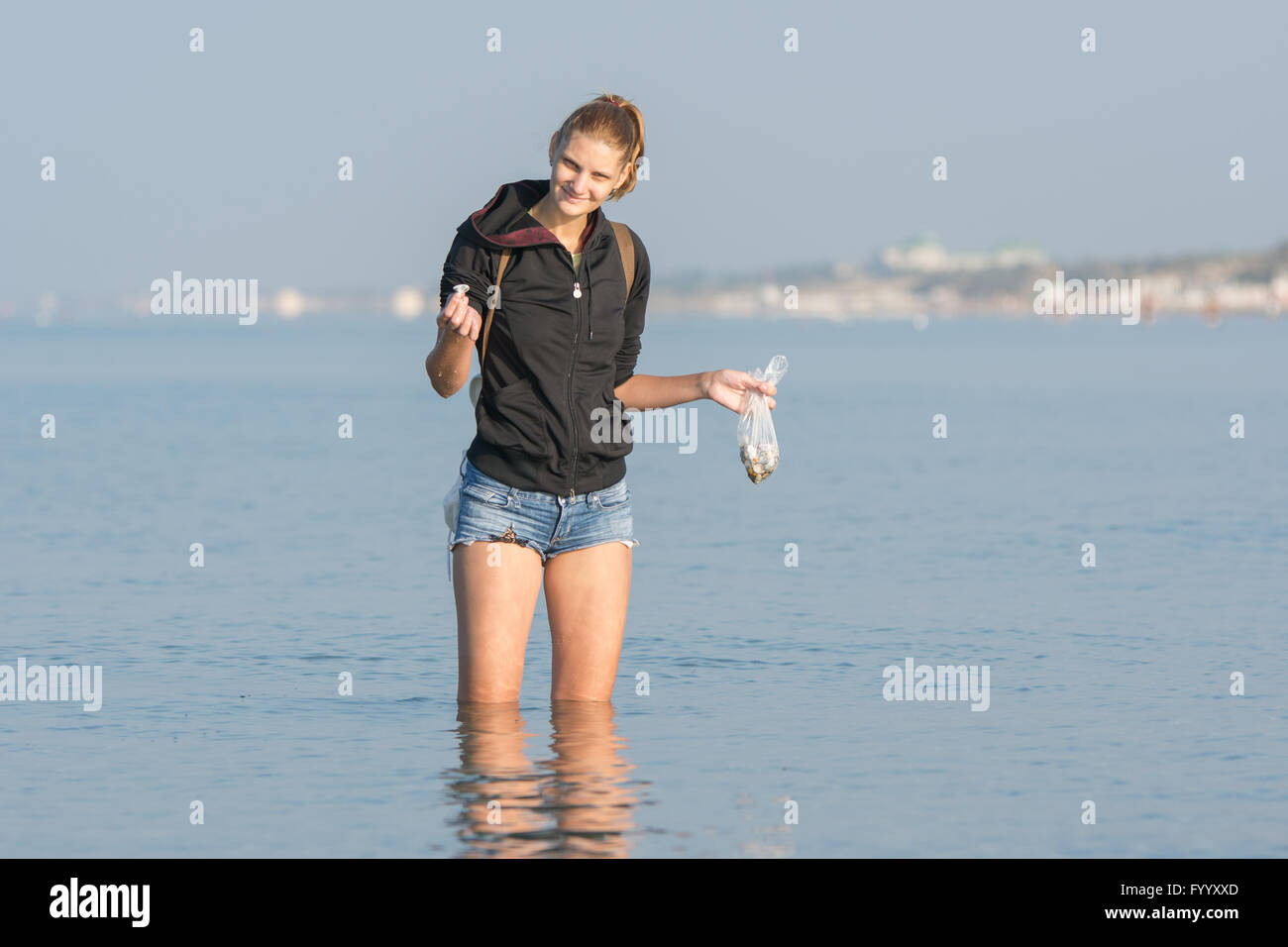 She collects shells at the sea early in the morning Stock Photo