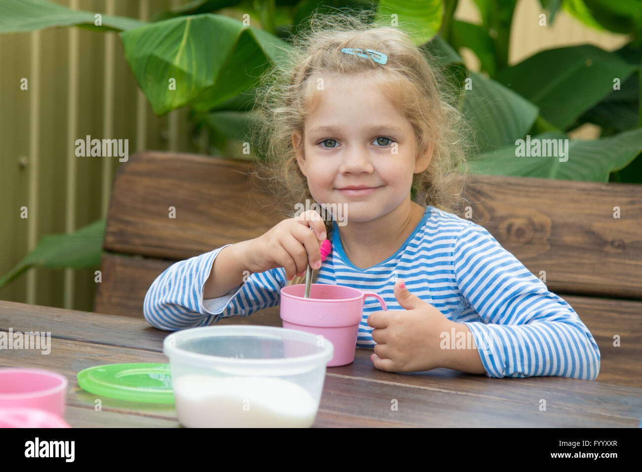 The four-year girl in tea interferes with sugar for breakfast Stock Photo