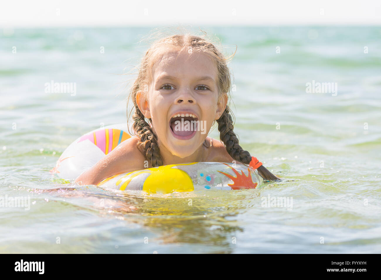 Six year old girl bathing in the sea with his mouth open in pleasure Stock Photo