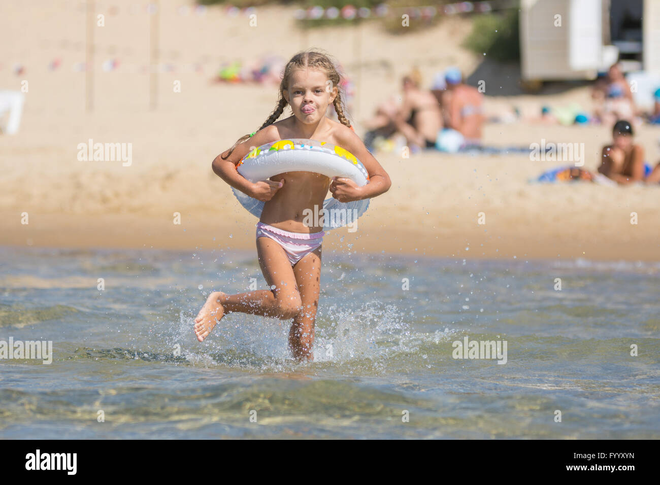 Six-year girl runs with a swimming circle swim in the sea Stock Photo