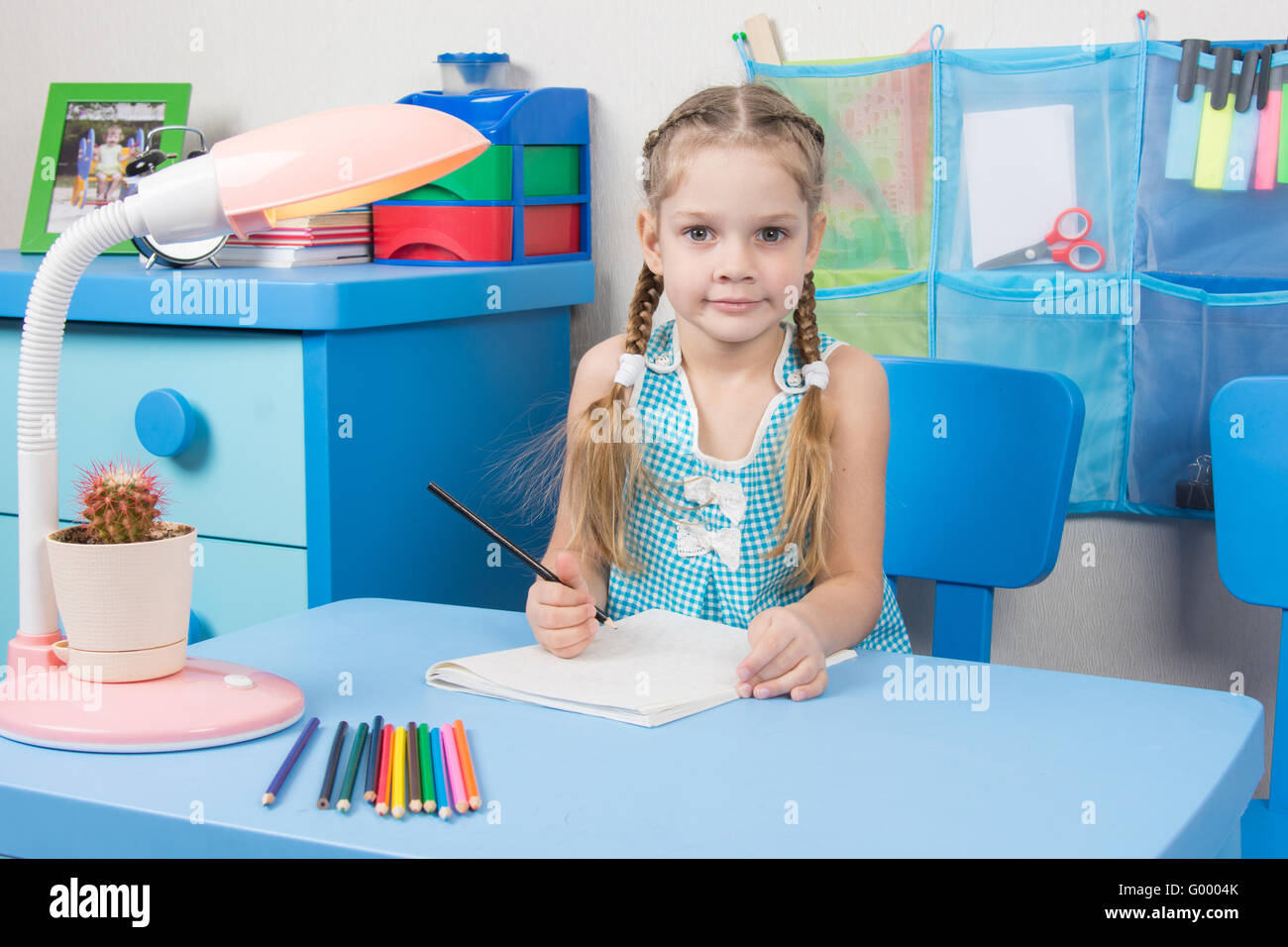 Five-year girl draws pencil in a notebook and looked into the frame Stock Photo