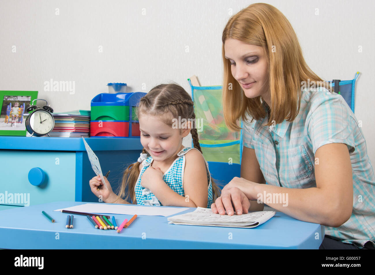 Girl enjoys painting with teacher in kindergarten Stock Photo