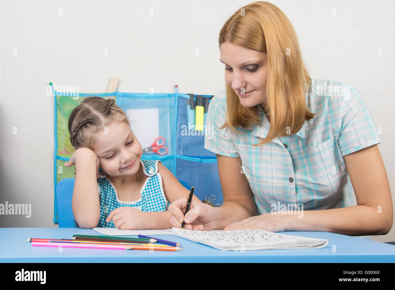 A young girl explains the five-year girl how to write letters Stock ...