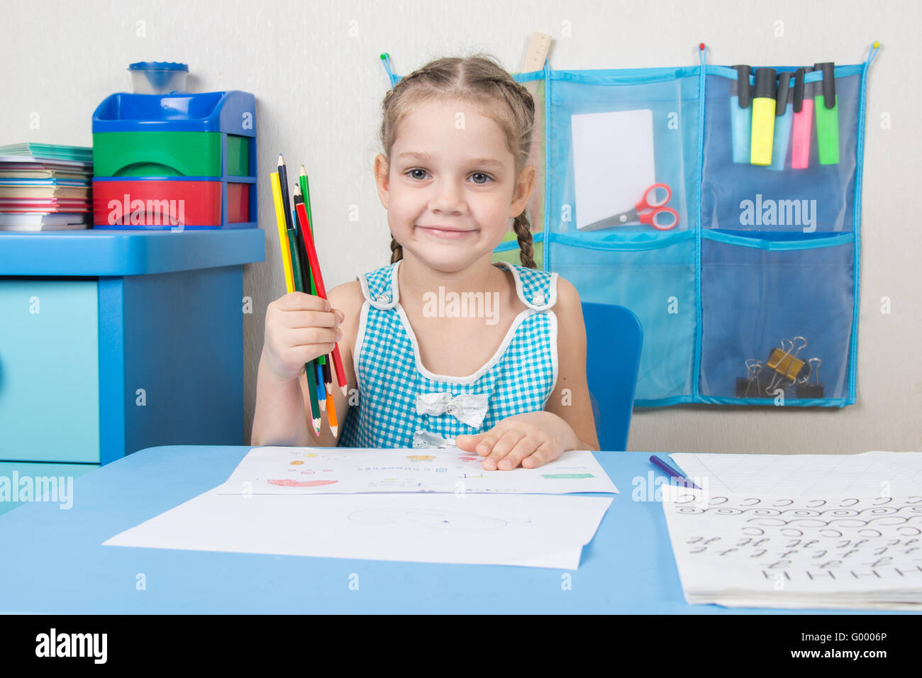 Happy five year old girl picked up a colored pencil and looked into the frame Stock Photo